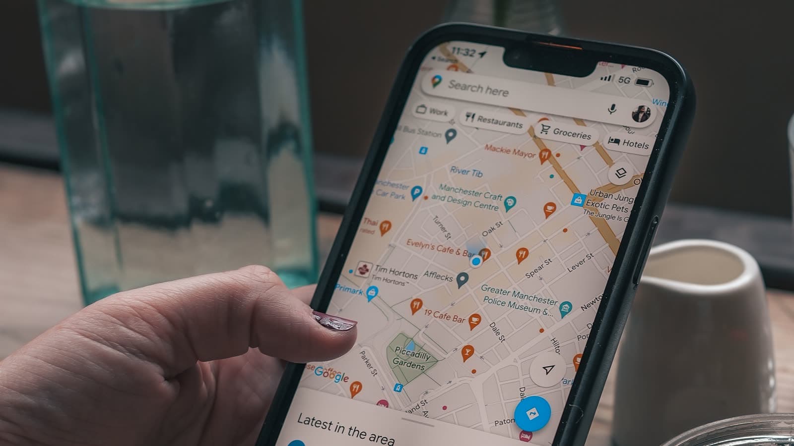 Mano sosteniendo un móvil con Google Maps abierto, mostrando los negocios señalados en el mapa de una ciudad
